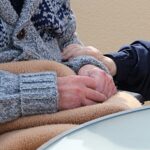 woman holding old woman's arm while she sits in wheelchair