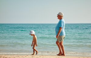 old man walking on beach with little boy