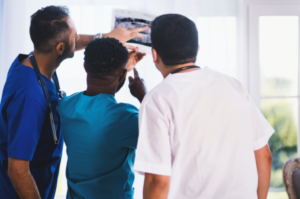 three medical professionals looking at x-ray results