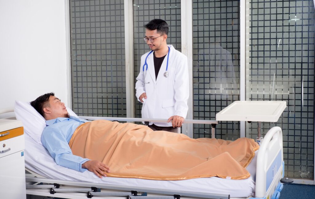 man lying in hospital bed talking to doctor