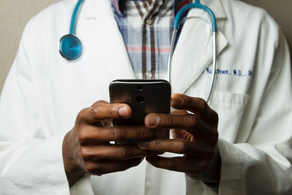 black doctor holds smartphone