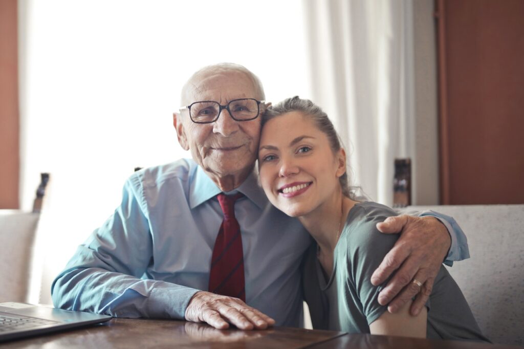 senior man hugs young woman with arm around her shoulder