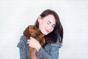 woman in gray sweater hugging her puppy