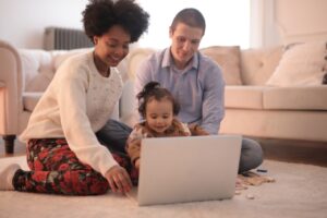 multicultural family sitting on floor with laptop