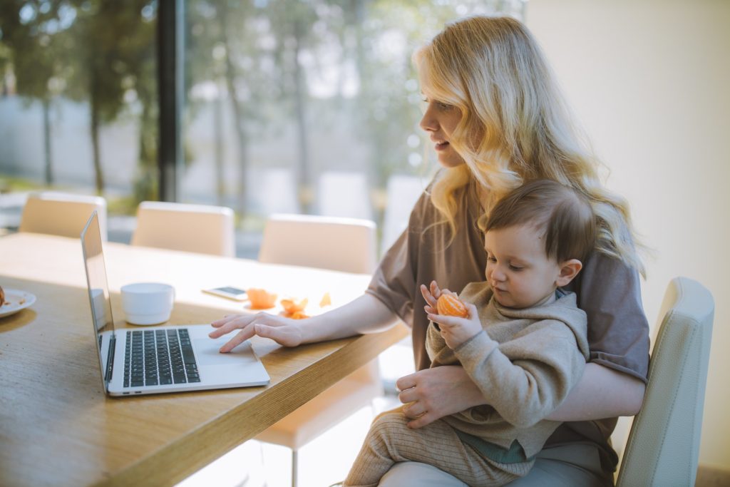 Woman holding her baby and Working on a Laptop