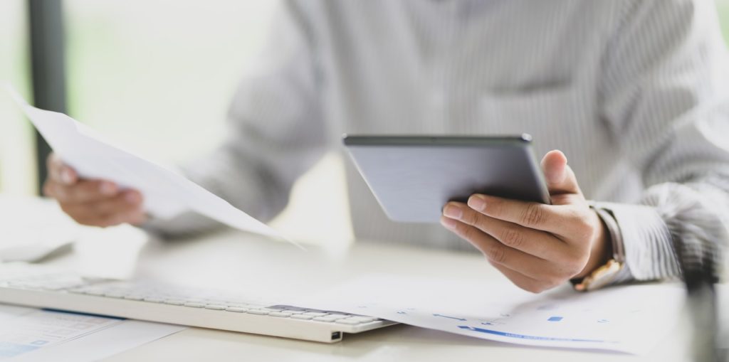 man in white shirt holding tablet and document