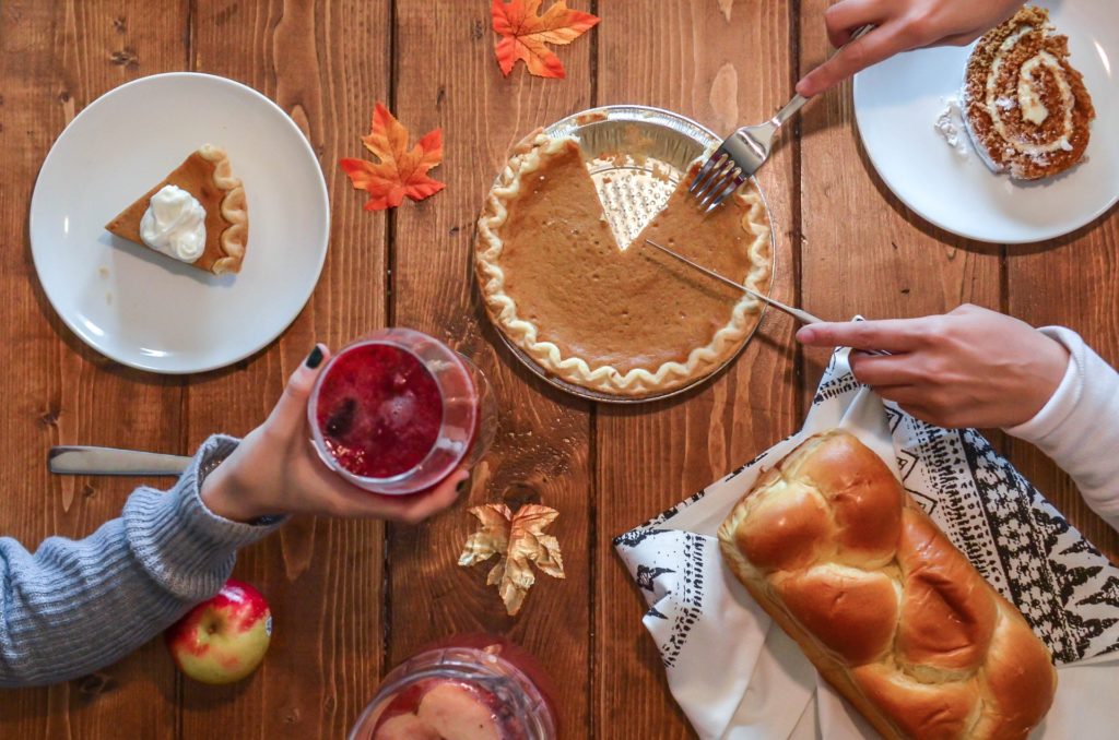 people slicing pumpkin pie on a thanksgiving table