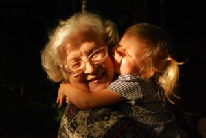 old woman embracing young, smiling girl