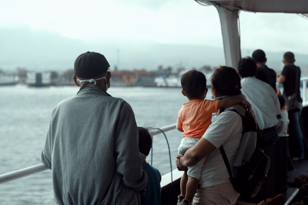 old man and woman with two children look toward the port from a boat deck