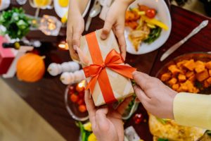 hands passing gift box over a holiday table