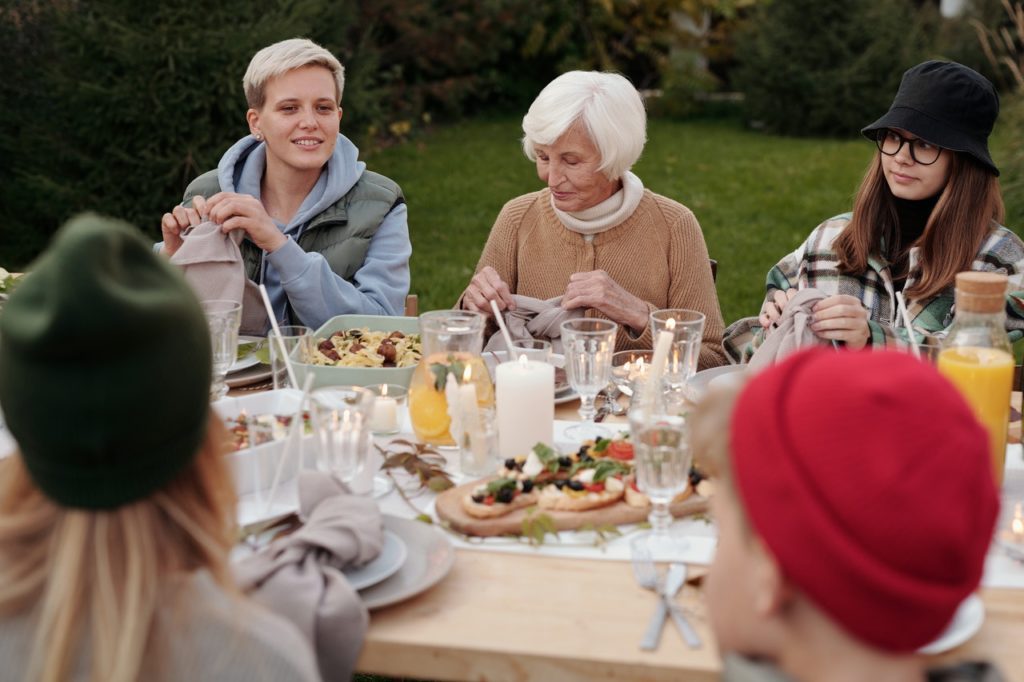cheerful family enjoying dinner party together in countryside