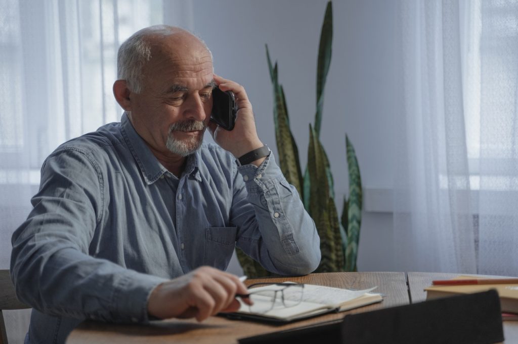 man in blue dress shirt holding black smartphone