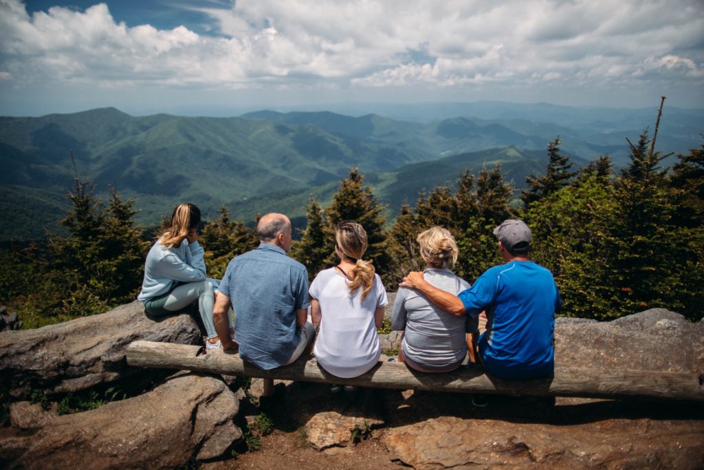 family sitting together on a ridge overlooking a mountain view