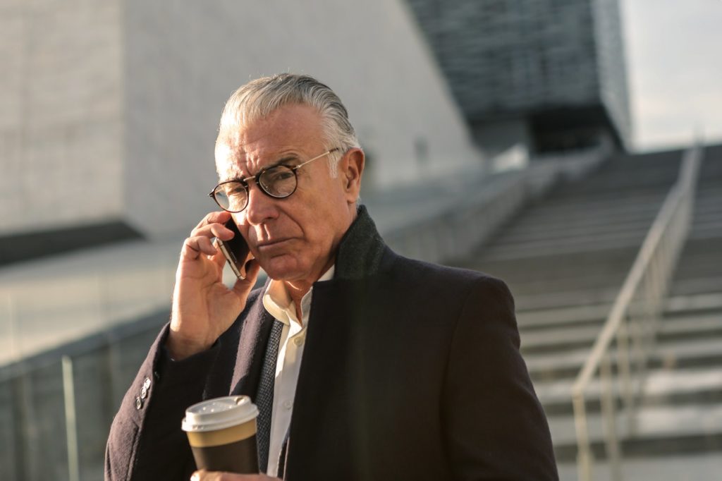 man in black suit jacket wearing eyeglasses holding a coffee