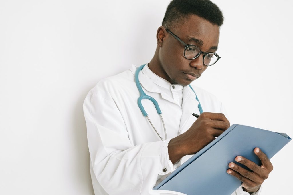 man in white scrub suit holding silver ipad