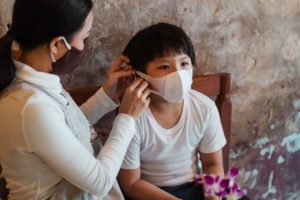 asian woman putting face mask on son