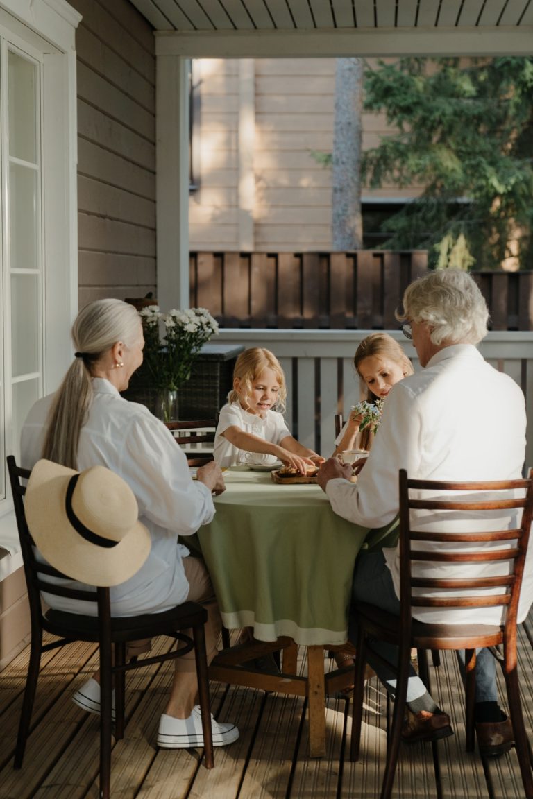 man in white dress shirt sitting on chair beside woman with grandchildren across the table