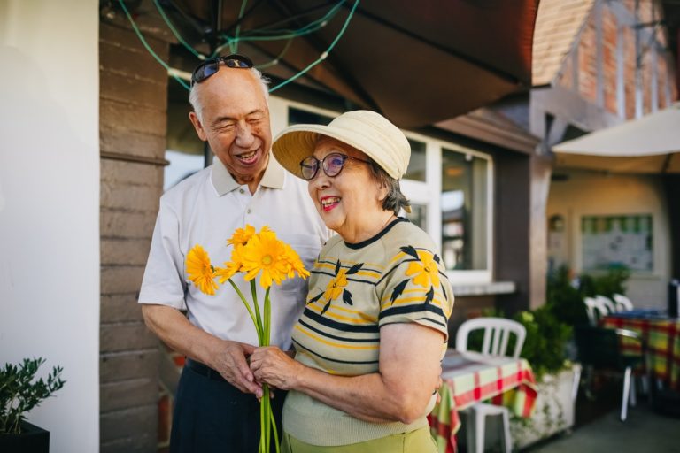 elderly couple holding bouquet of flowers while holding hands