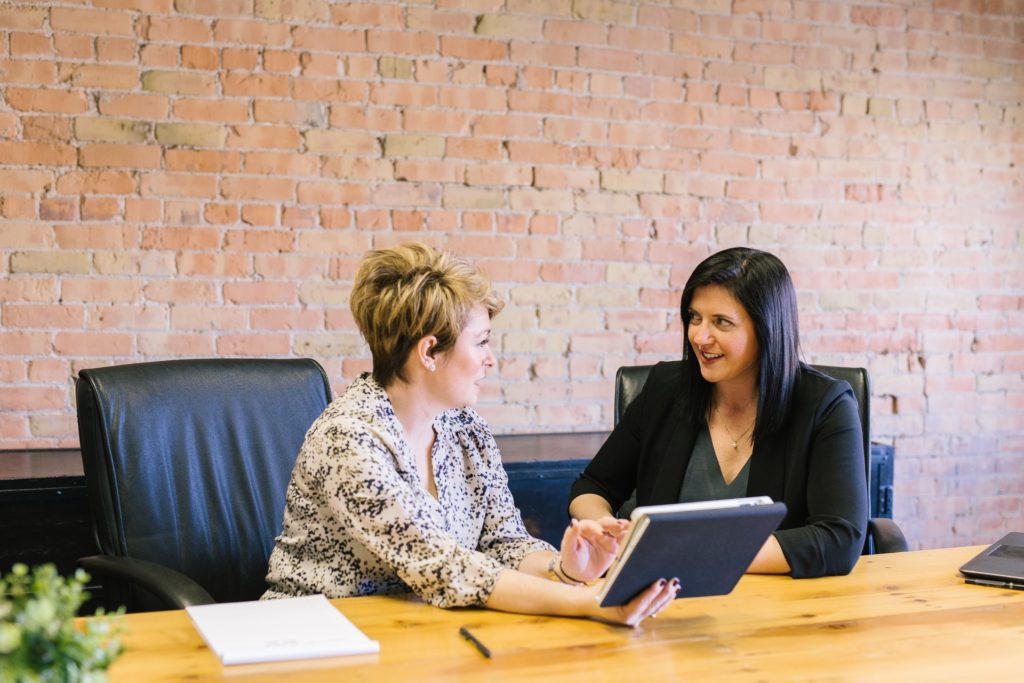 two women looking at a tablet in an office