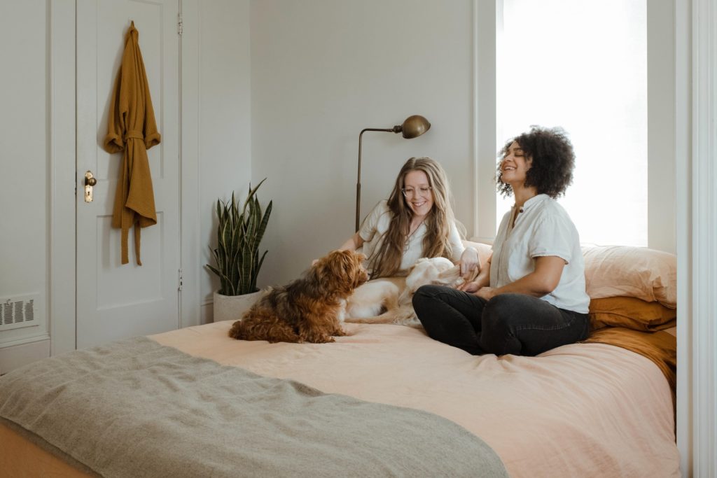 two women sitting on bed with two dogs