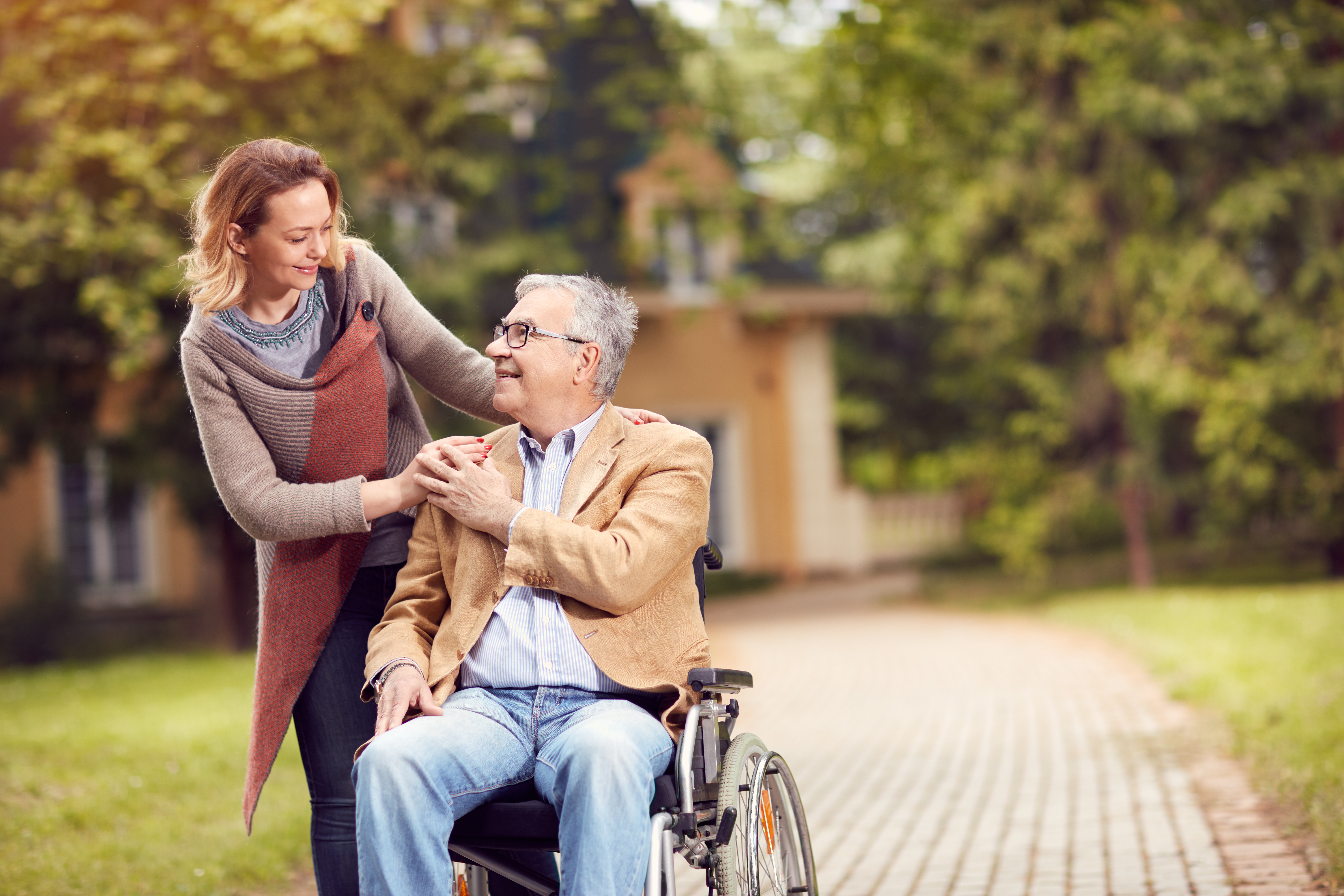 middle-age woman sharing a smile with older man in wheelchair
