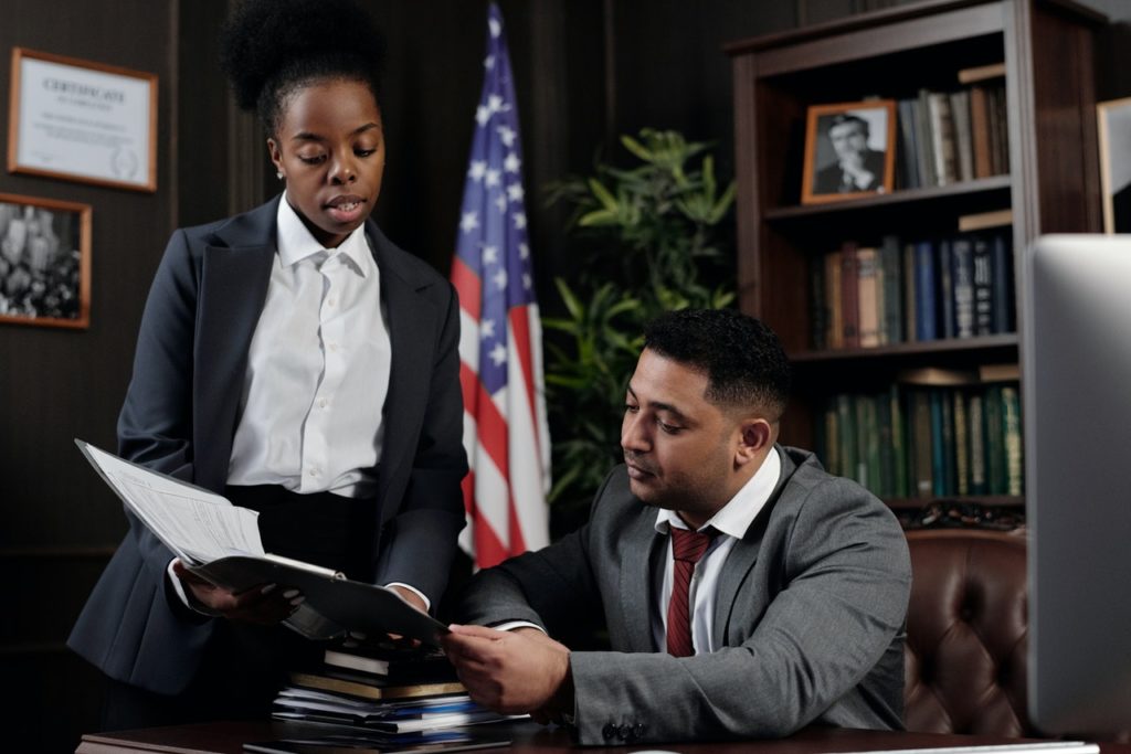 black female attorney and ethnic male attorney review documents in a law office