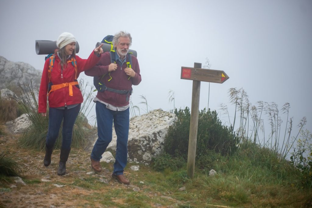 older couple hiking on misty mountain trail