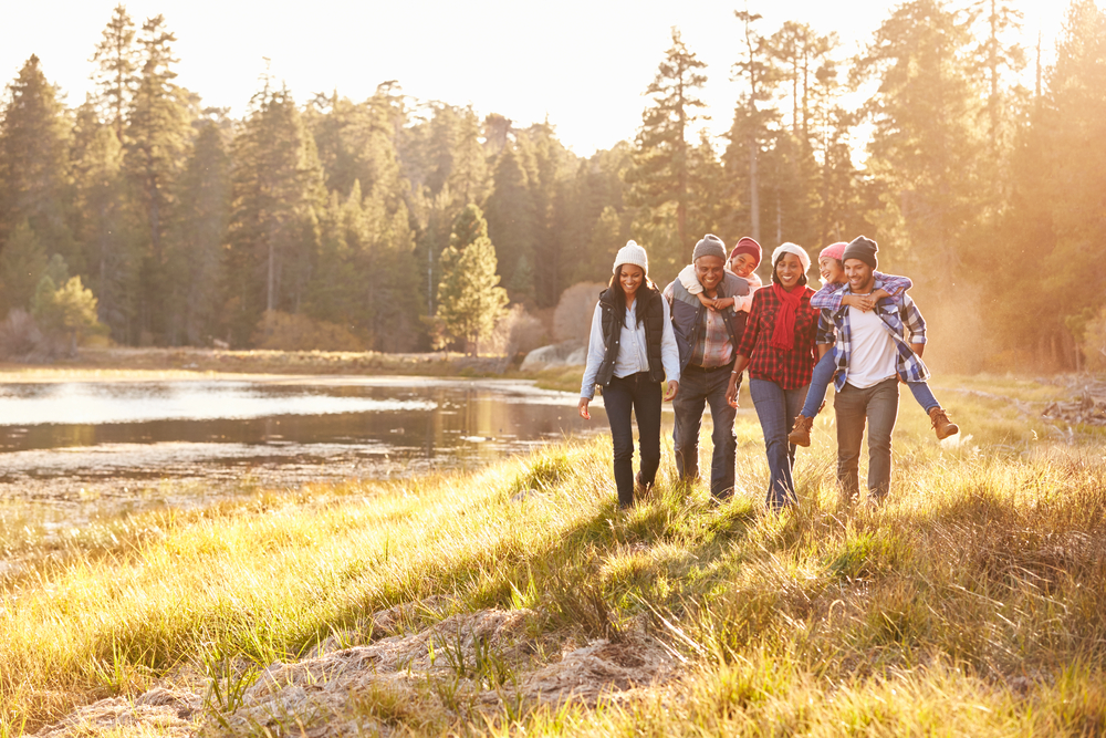 multi generational black family walks along a river in the woods