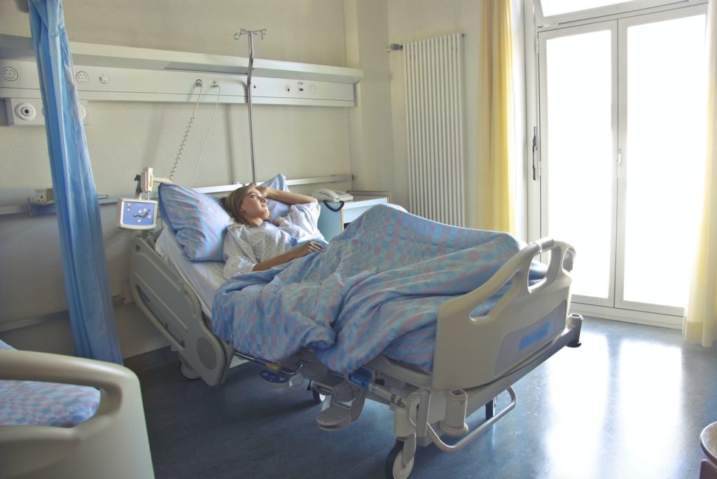woman lying in hospital bed in bright room