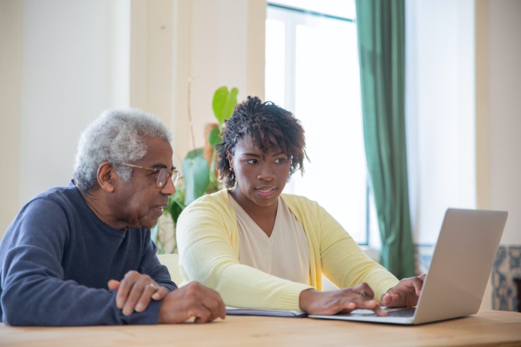 old black man and younger woman looking at laptop together