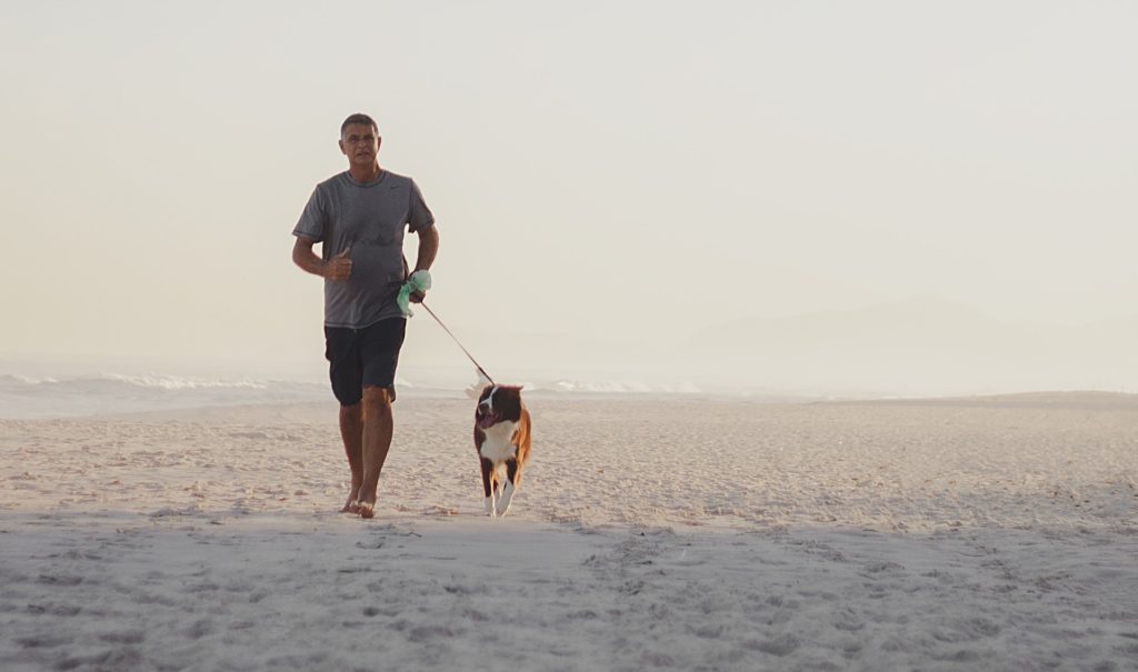 man walking with dog on beach