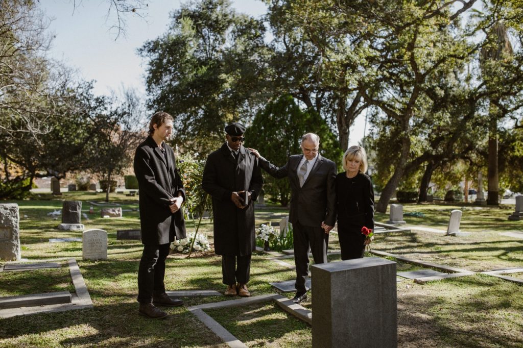 family gathered around a grave for funeral service