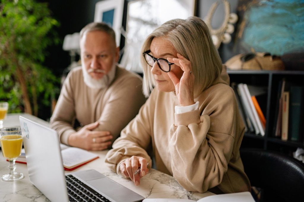 old couple sitting beside each other working on laptop