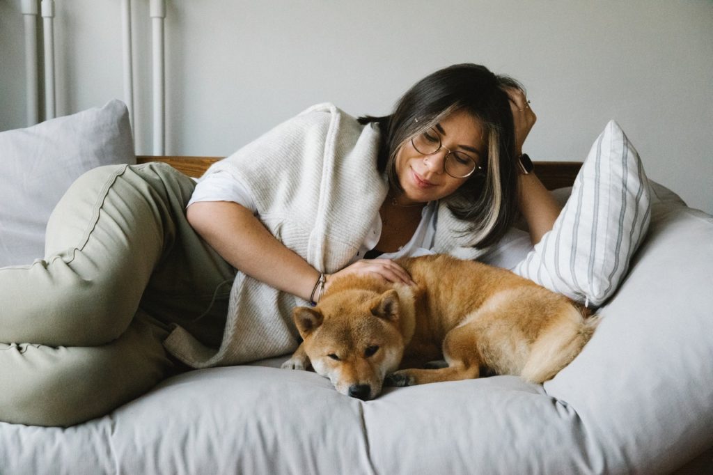 woman lying on couch cuddling dog