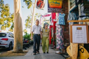 older asian couple walking on sidewalk by shops