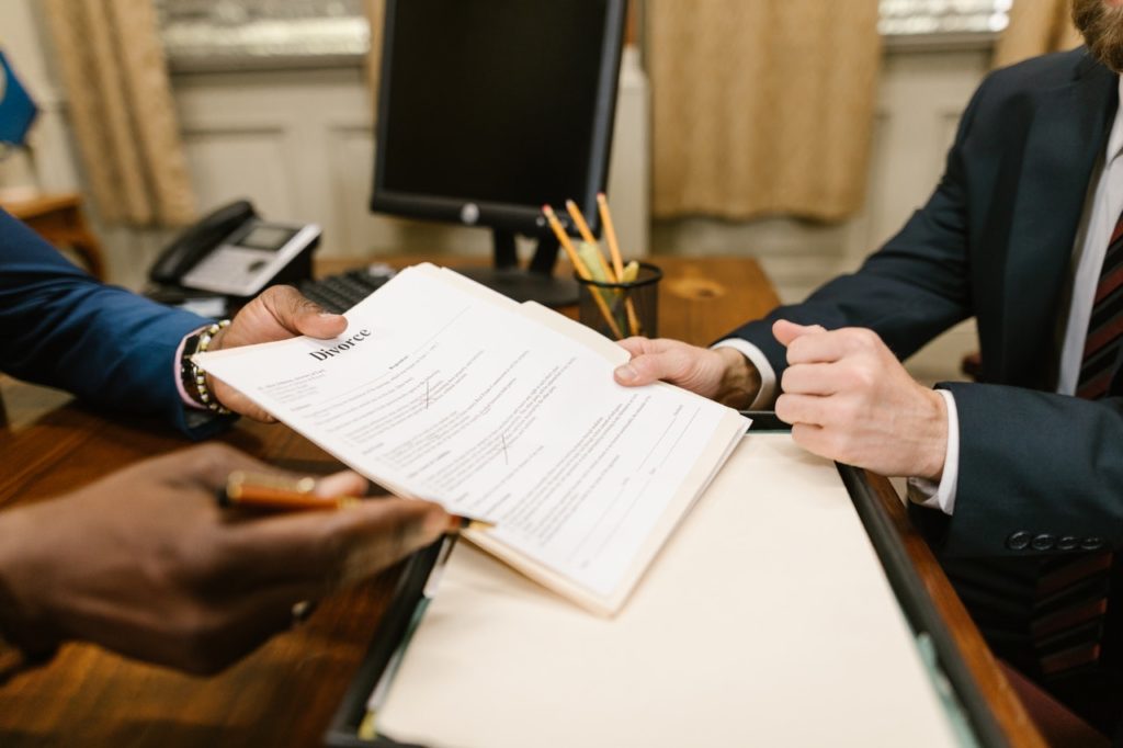 man handing woman divorce documents in a legal office