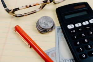 red pen glasses and cash with a calculator