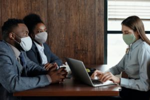 black man and woman sit at desk with a woman on laptop