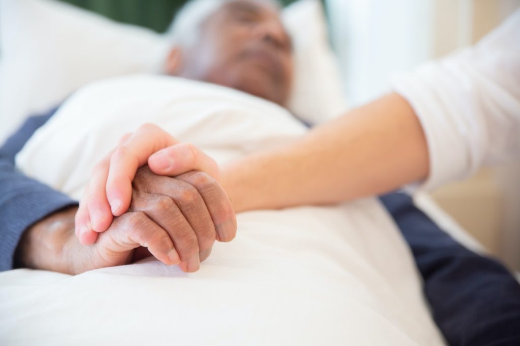 woman holding hand of man in bed