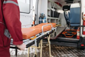 man pushing stretcher into back of ambulance