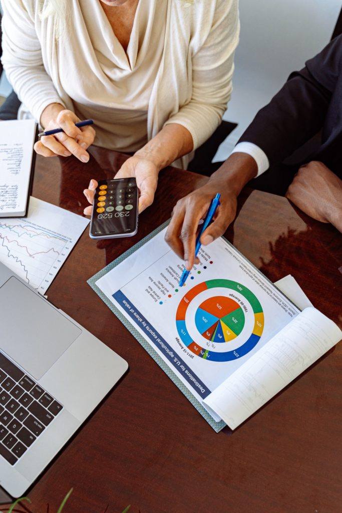 man and woman look at financial chart with laptop and calculator