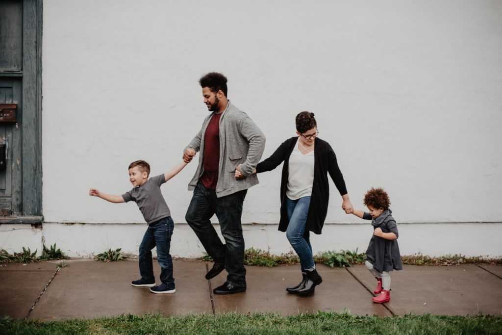 family of four walking down the sidewalk holding hands