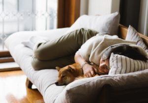 woman sleeping on sofa with pet dog