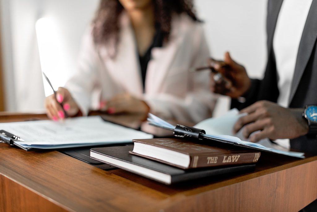 woman and man review documents with a law book on the table in front of them