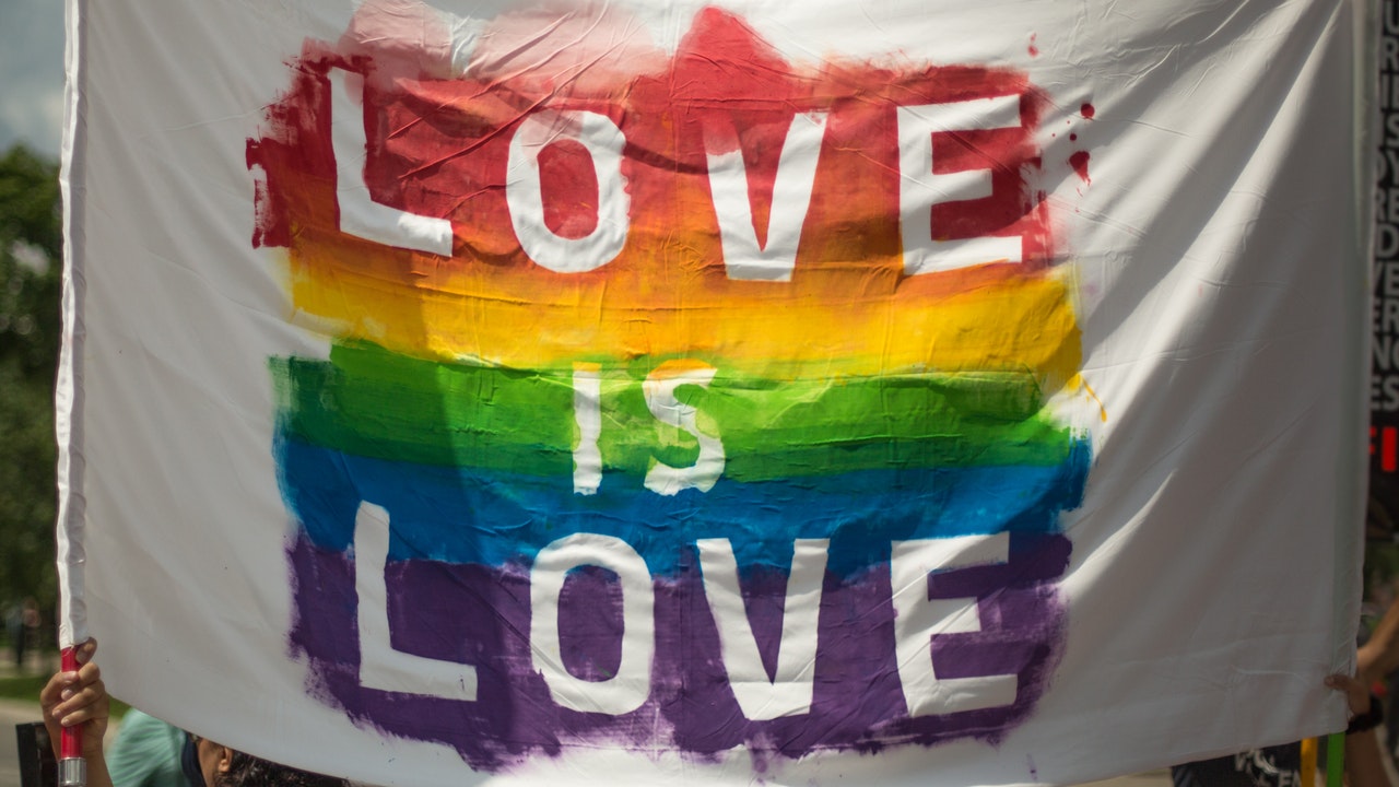 handpainted white sign with rainbow and "love is love" message