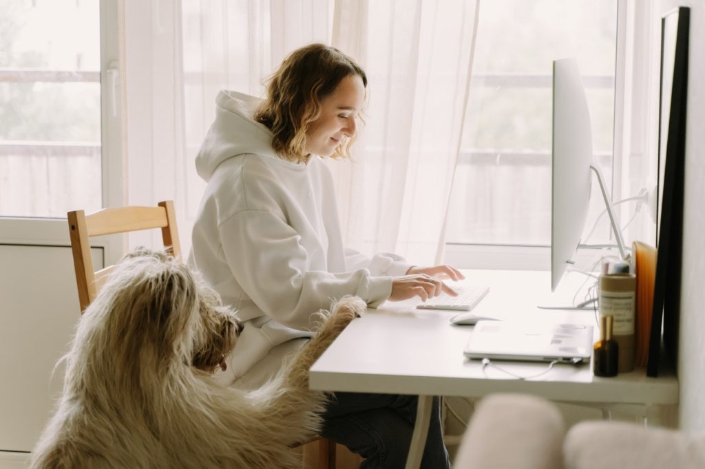 young woman sitting at desk with dog next to her