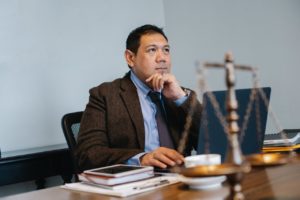 asian male attorney looks up pensively while sitting at legal desk