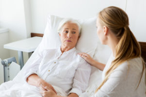 older woman in hospital bed with younger woman comforting her