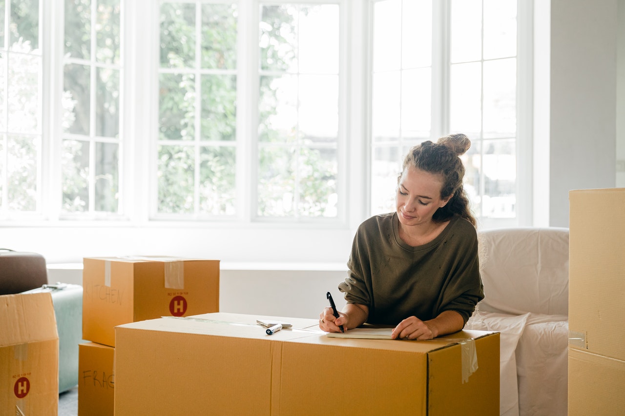 woman making notes while packing moving boxes
