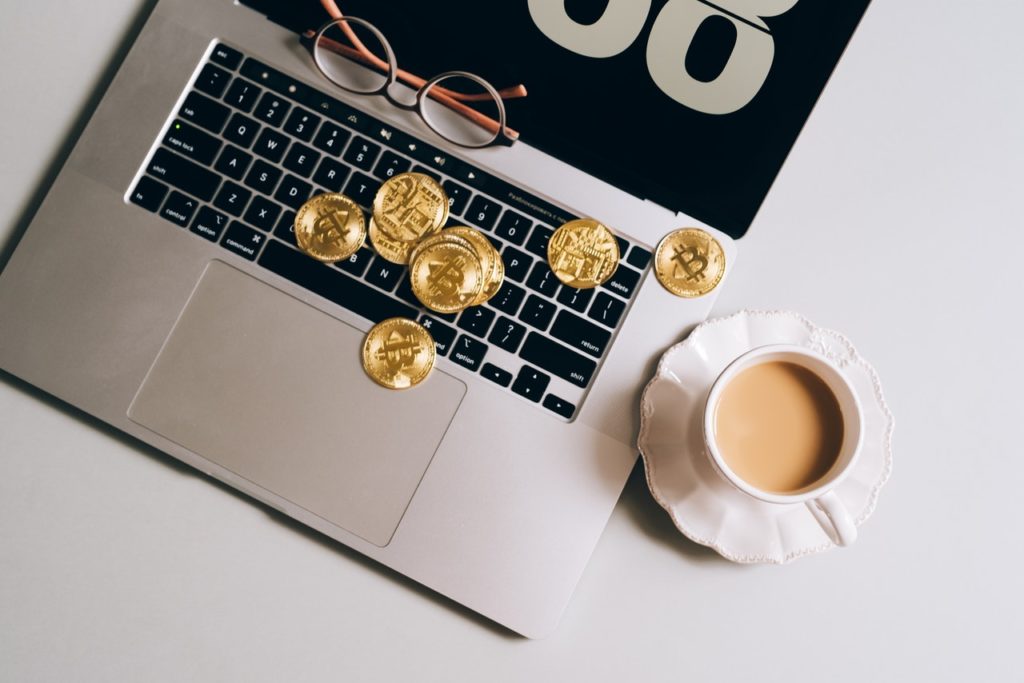 bitcoin scattered on a laptop with a cup of tea nearby